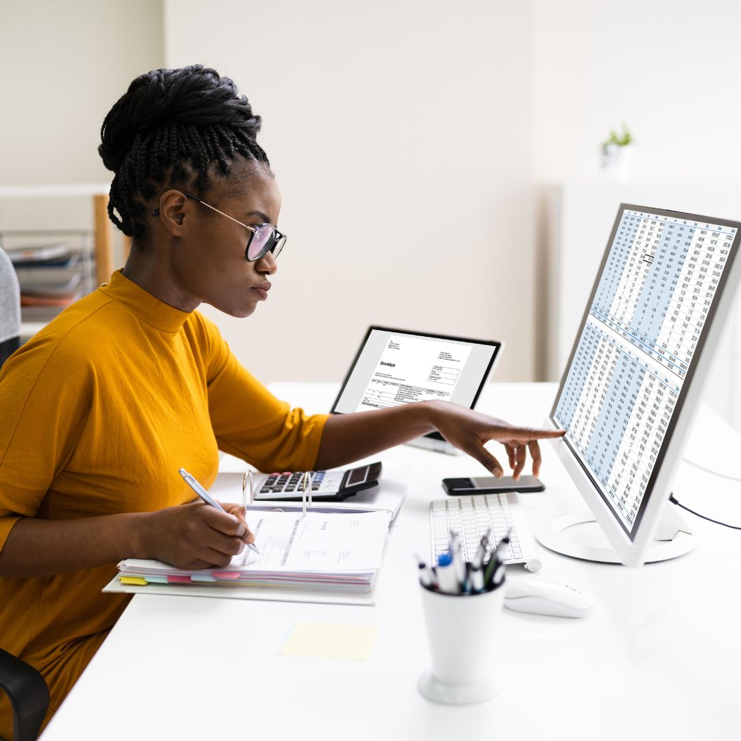 Woman in yellow sweater looking at spreadsheets on her computer