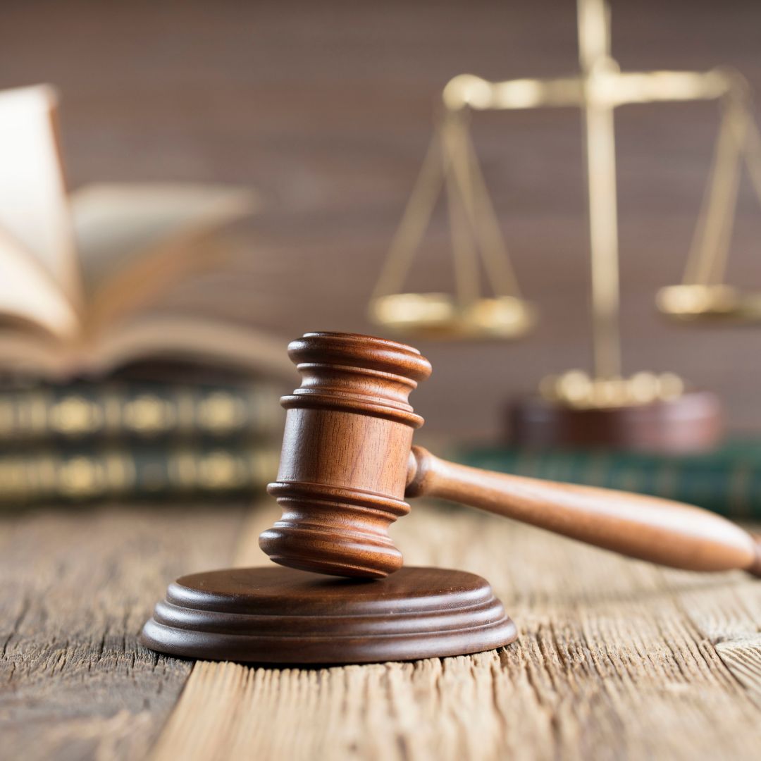 Close up of a gavel on a desk in front of a stack of books and an old scale
