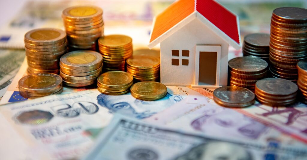 toy house on a pile of money and coins