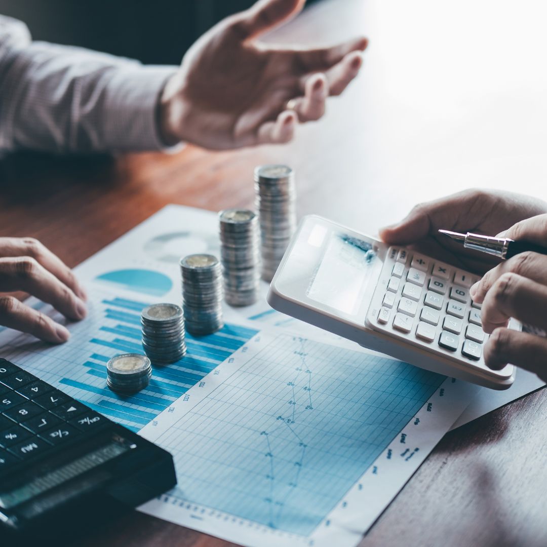 financial planner and client talking with financial plan and coins on a desk
