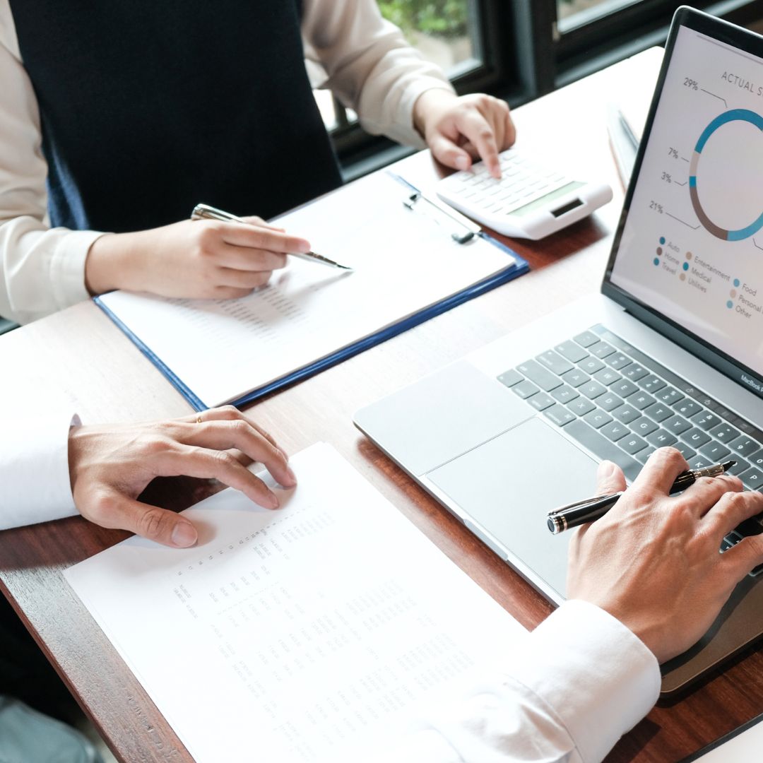 people looking at financial numbers on papers and a computer