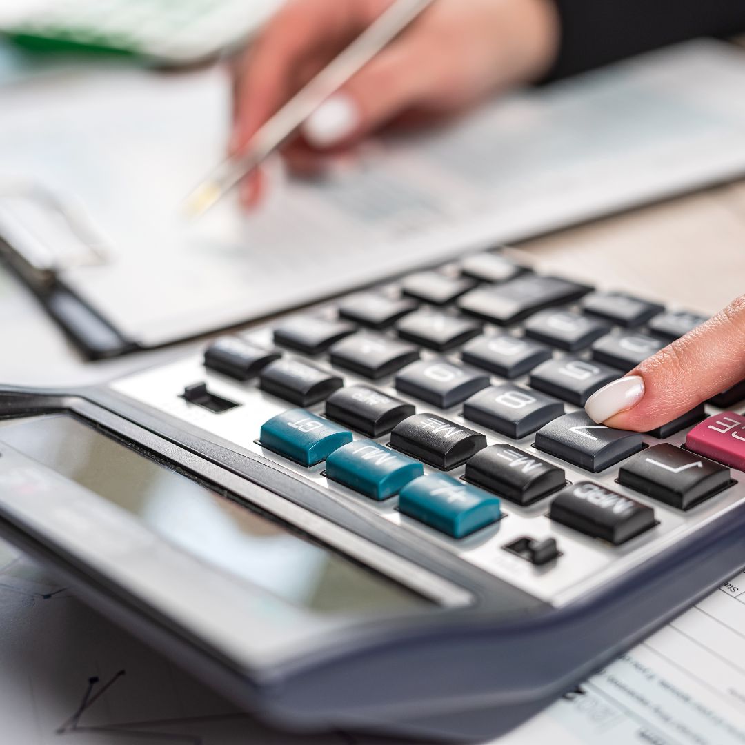 a person writing while using a calculator