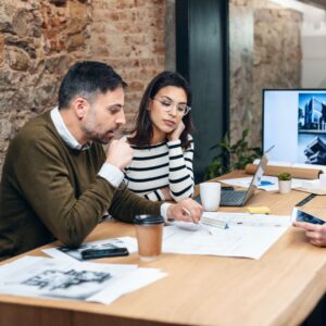 people sit side by side at table looking at planning document