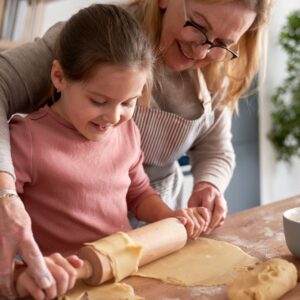 lady helps child roll out pie crust on counter