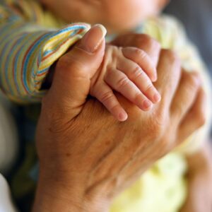 close up of adult hand holding small baby's hand