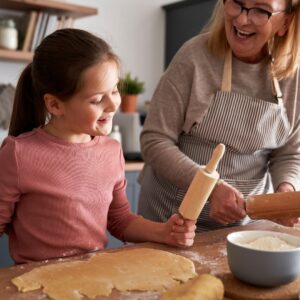mature woman with child smiling while rolling our pie crust