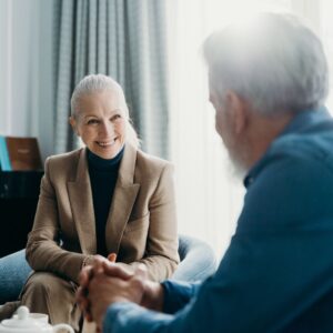 mature professional woman sits smiling at person seated opposite her