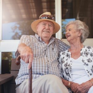 woman and man with a cane sit on bench side by side