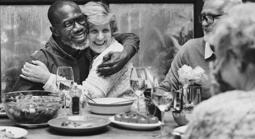 man and woman sitting side by side embrace at table