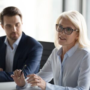 professionally dressed woman sitting at table holding pen