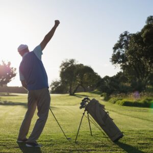 man playing golf holds club while throwing other hand up in the air