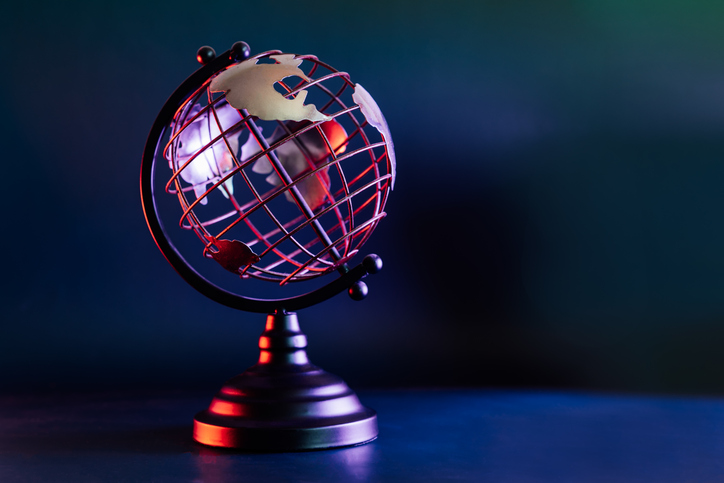 Metallic model of a globe with map in blue and red neon light. Bipolarity of the world. Geography concept. Selective focus, Copy space